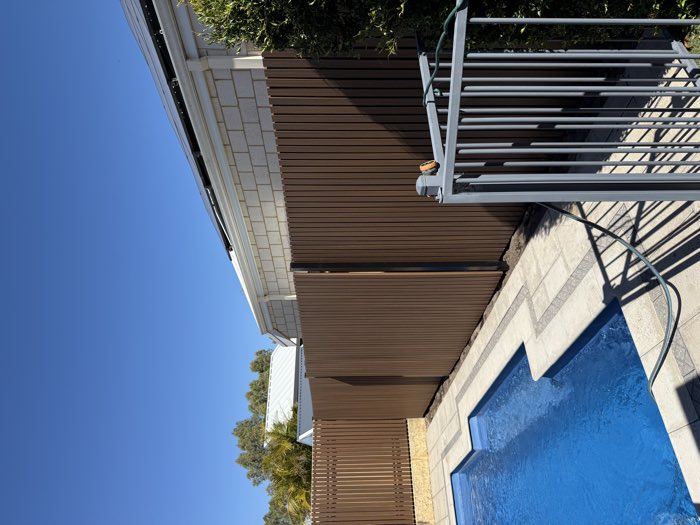 Slat screening installed over an existing boundary fence beside a pool