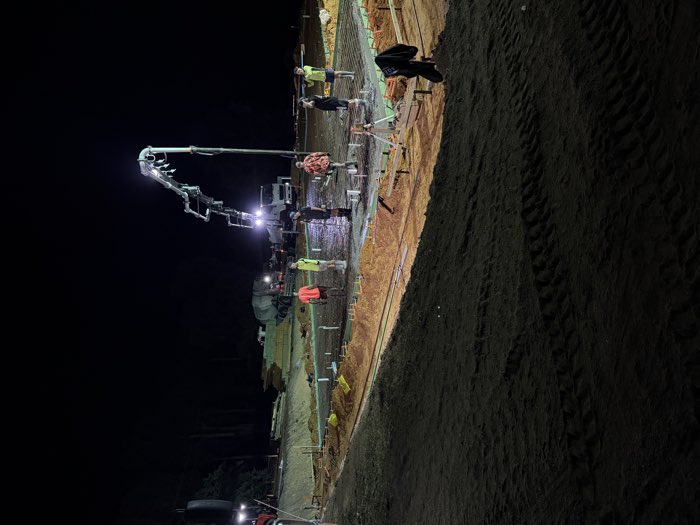 Concrete slab being formed and poured at night under floodlights