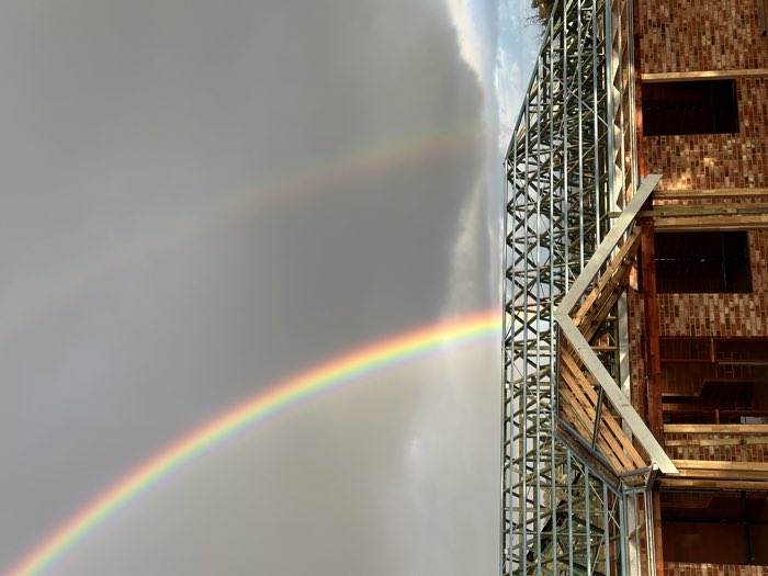 Roof truss frame installed on a brick home under a double rainbow